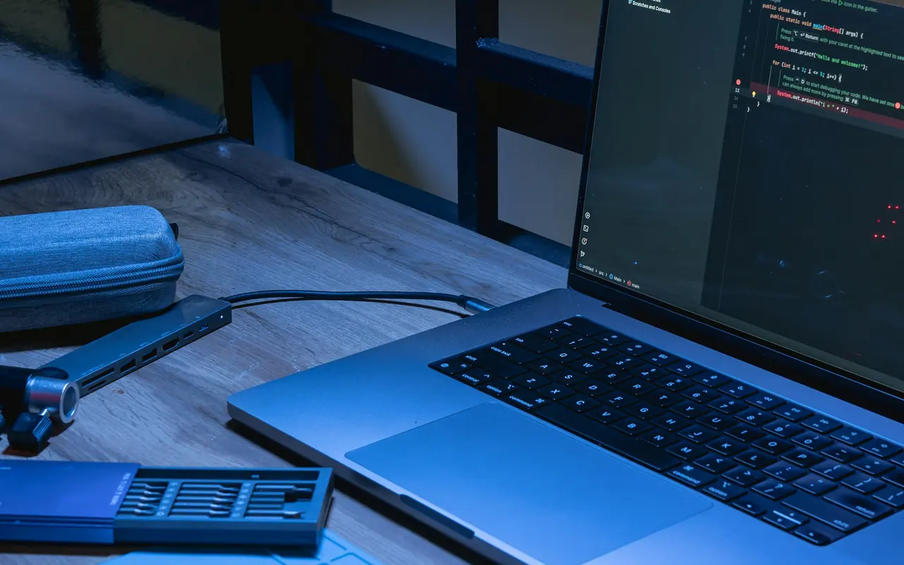 Laptop and phone on a wooden desk with source code on screen