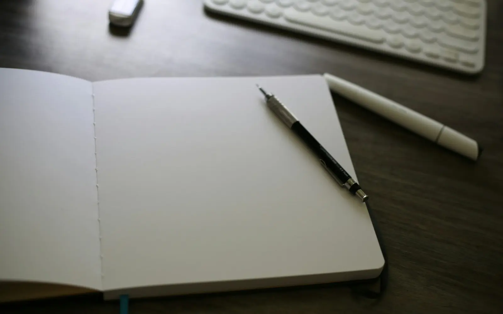 Open notebook and pencil beside a keyboard